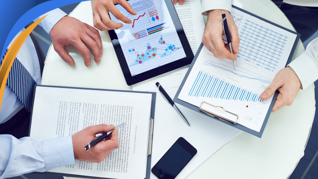 Sales leaders reviewing commission reports and performance charts on paper and a tablet