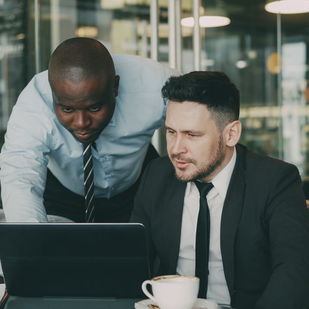 A sales manager reviewing numbers on a laptop with a team member