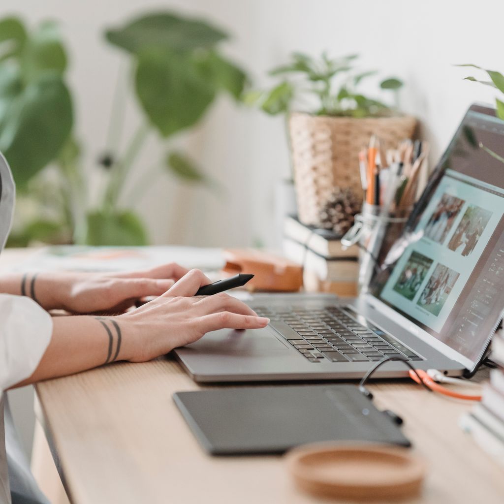 A designer working on a laptop with a drawing tablet