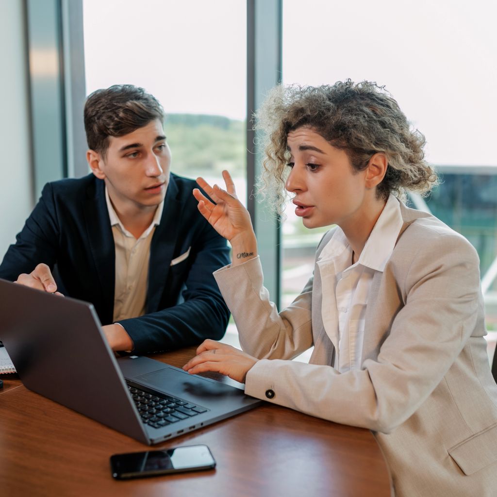 An account manager reviewing an account with a colleague at a laptop