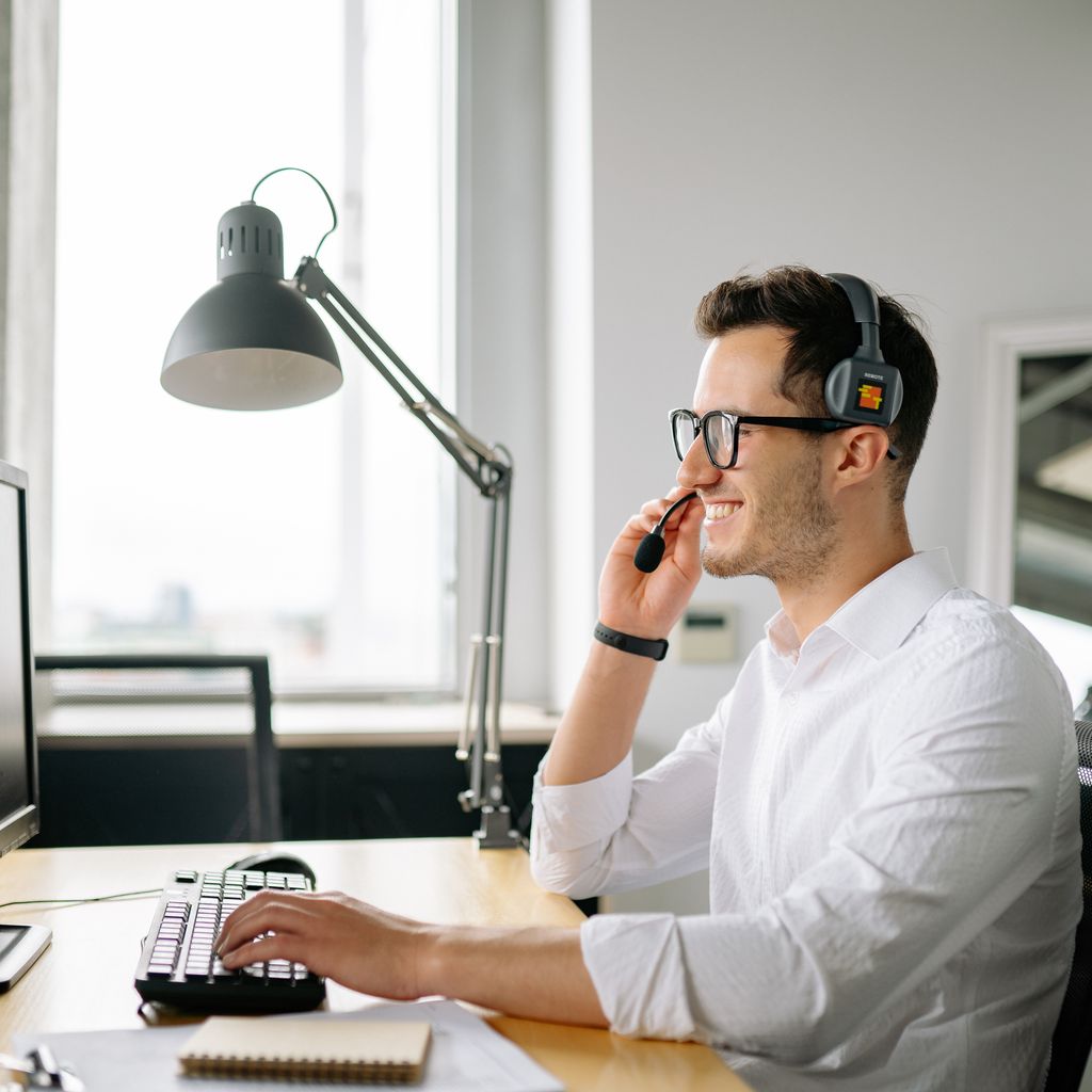 An SDR on a headset working a call at his computer