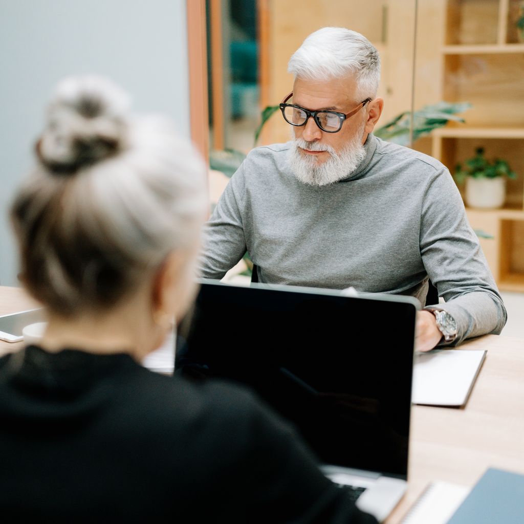 A senior technical leader reviewing work with a colleague at a meeting table