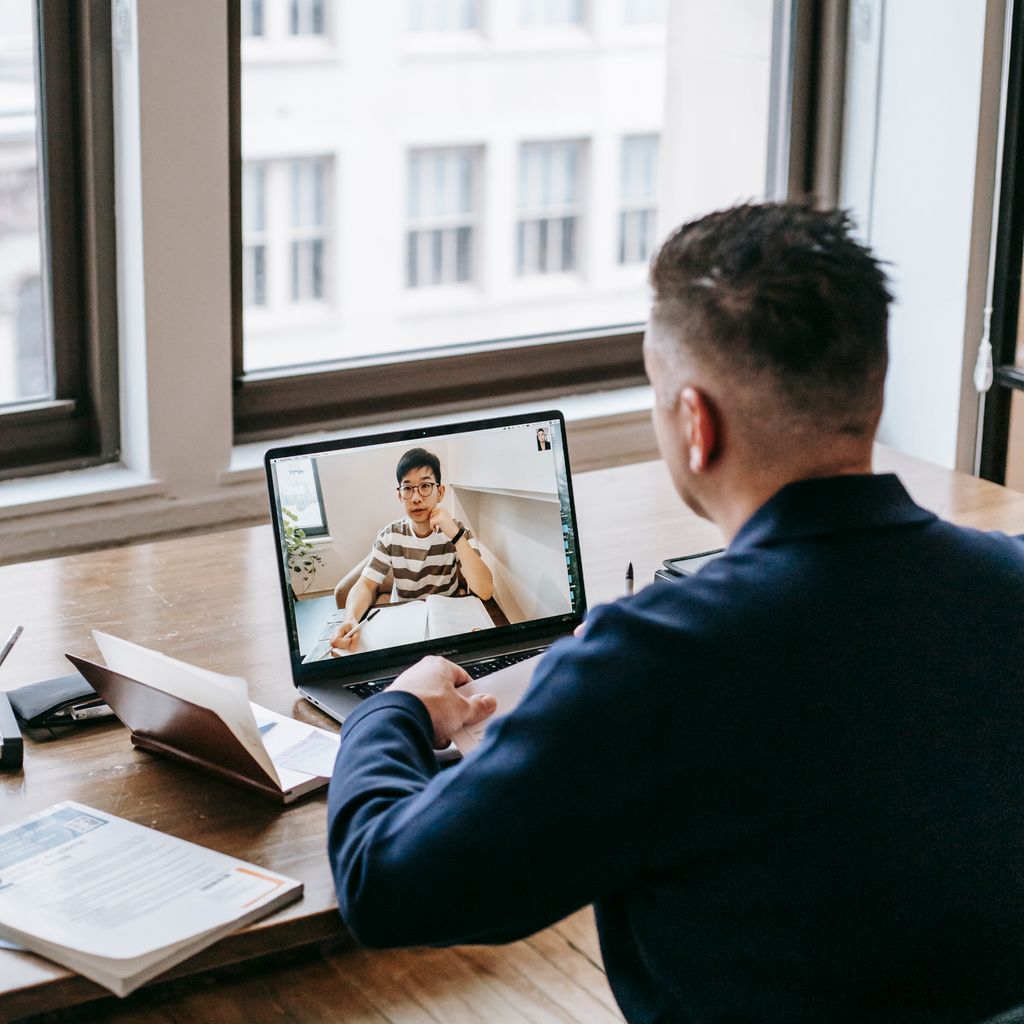 A customer success manager on a video call with a client at his desk