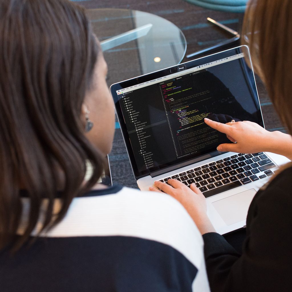 Two colleagues reviewing work together on a laptop