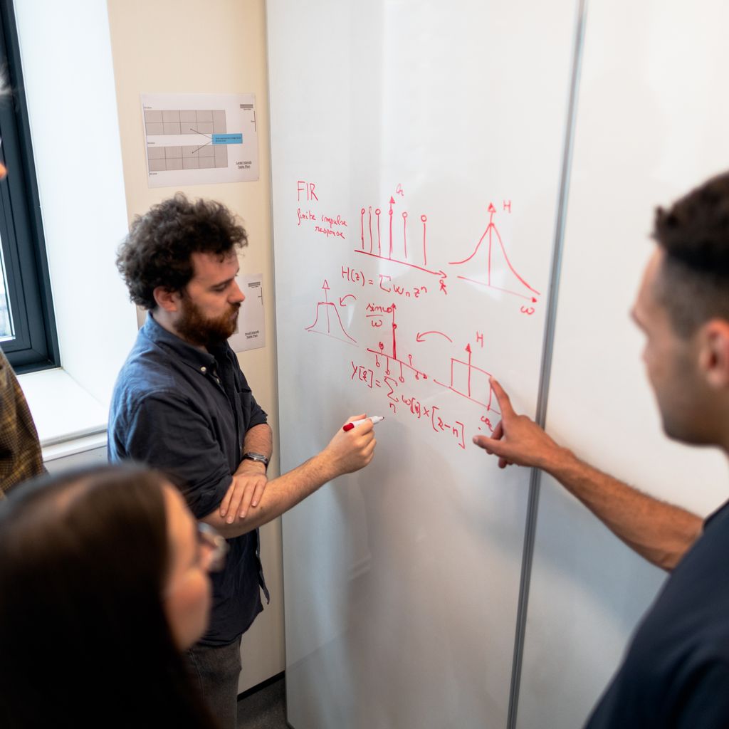 Engineers discussing a diagram on a whiteboard