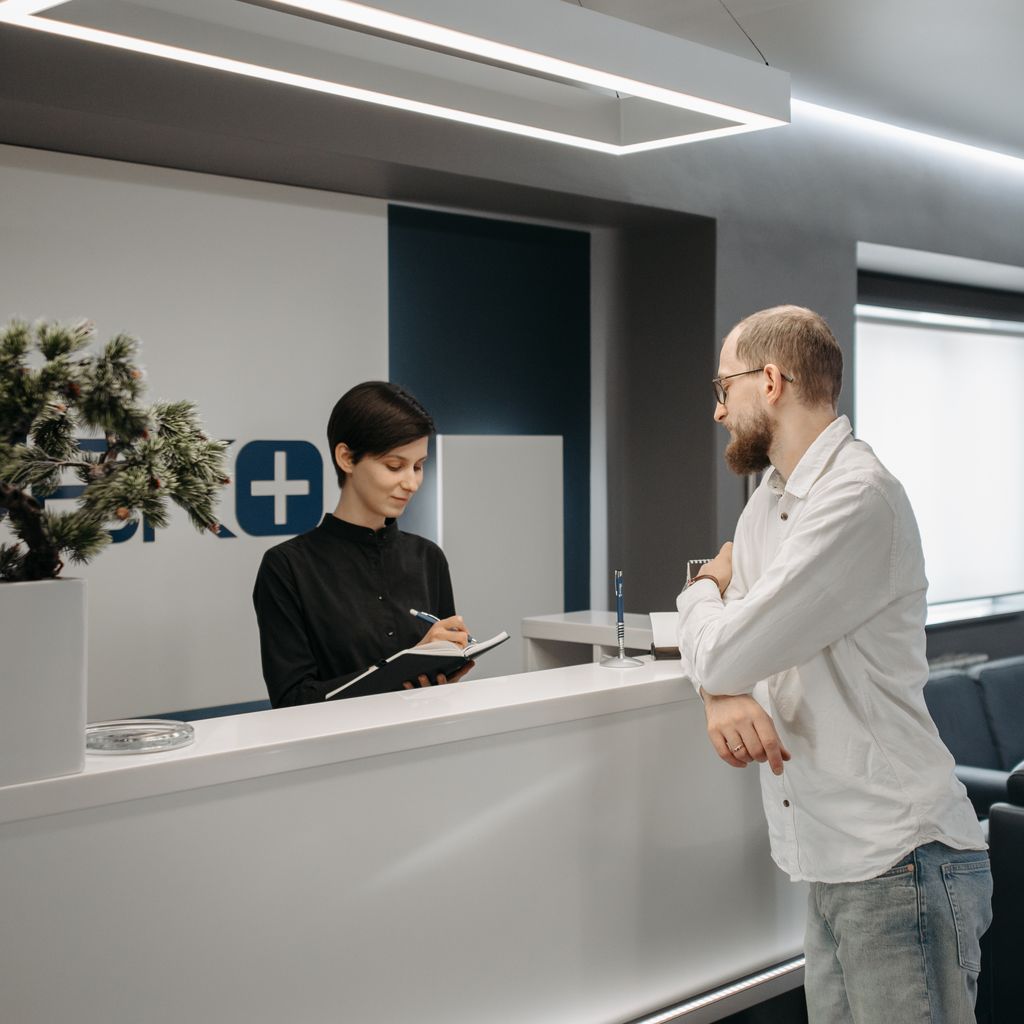 Front desk staff taking patient details at a clinic reception counter