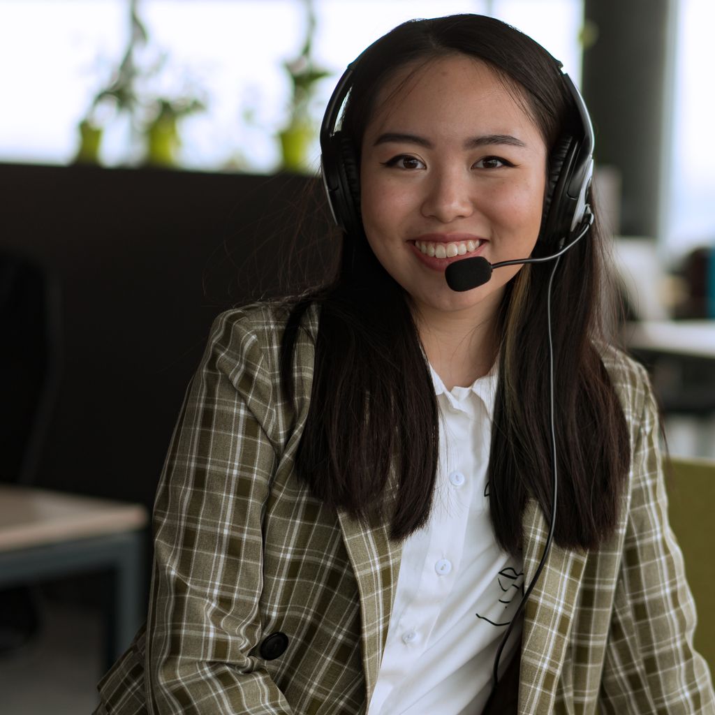 A support representative with a headset smiling at her desk