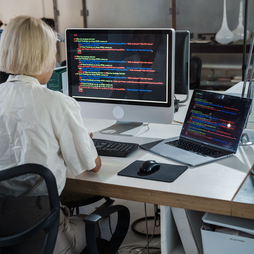 A developer working across a desktop monitor and a laptop