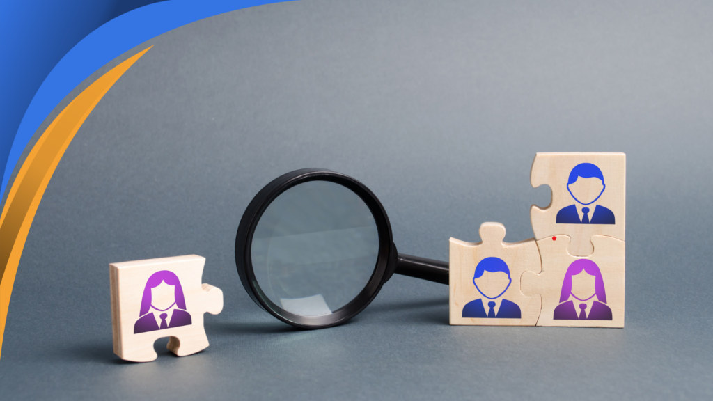 Magnifying glass between wooden puzzle pieces with employee icons, comparing in-house and remote hires
