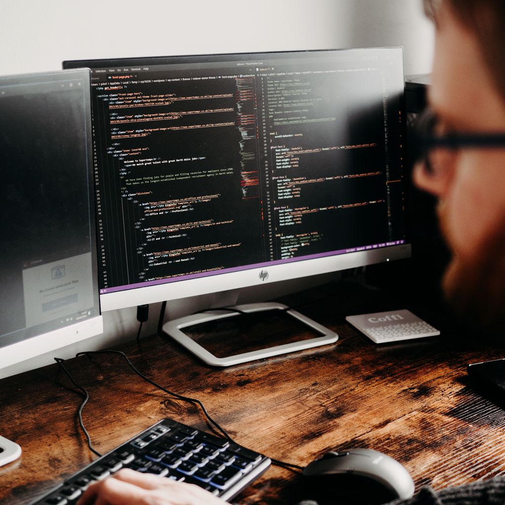 A developer typing at a desk with two monitors