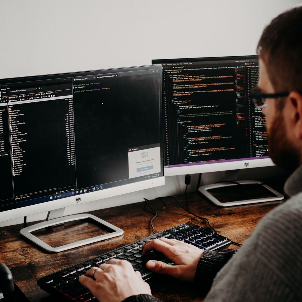 A developer typing at a desk with two monitors