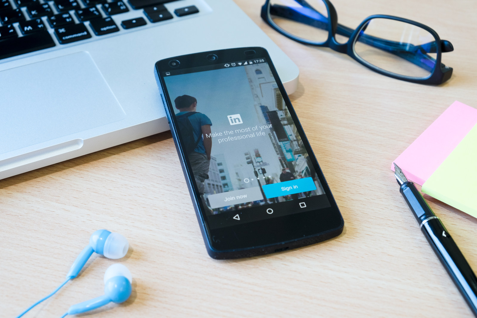 Smartphone showing the LinkedIn app on a desk next to a laptop