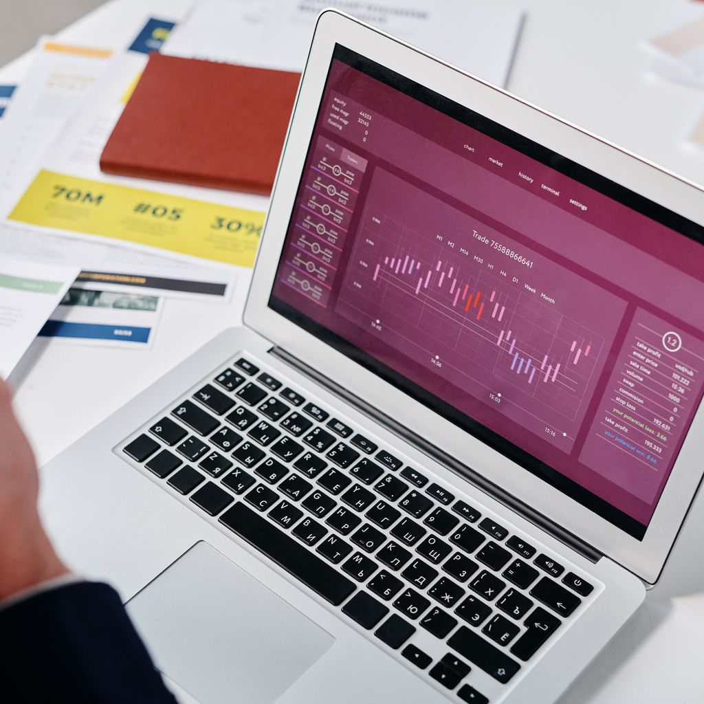 A laptop showing an operations dashboard on a desk with printed reports