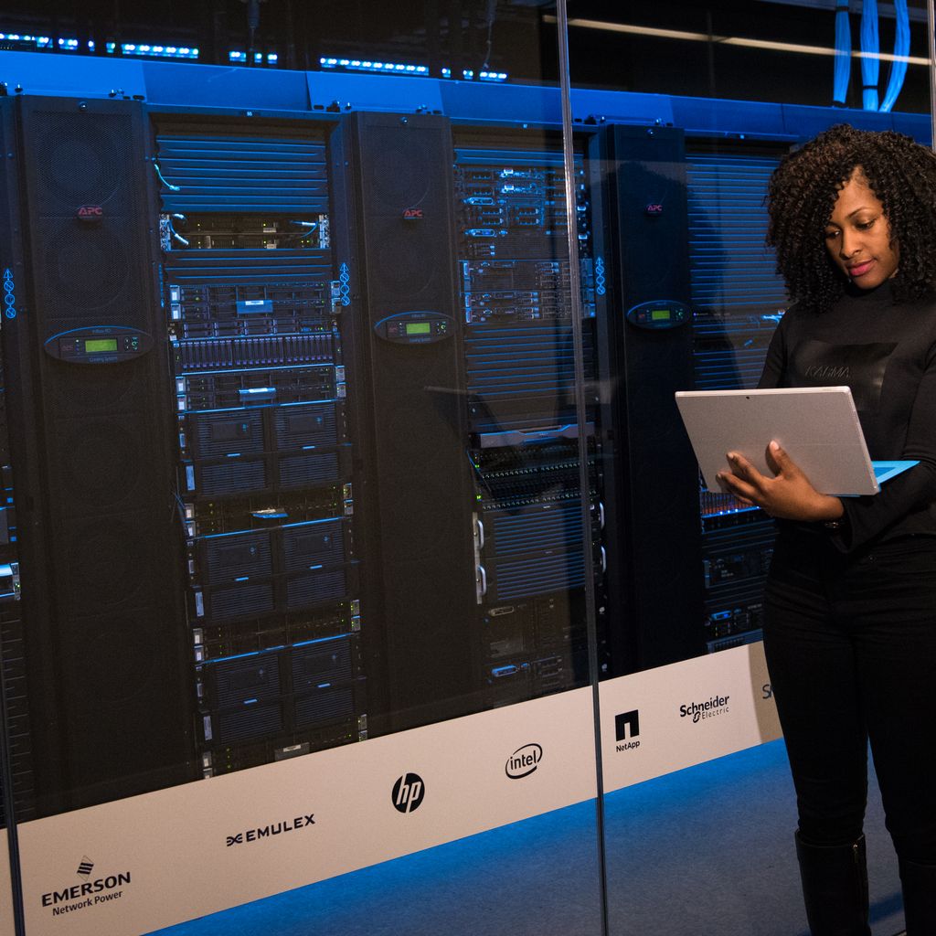 An engineer with a tablet standing beside server racks