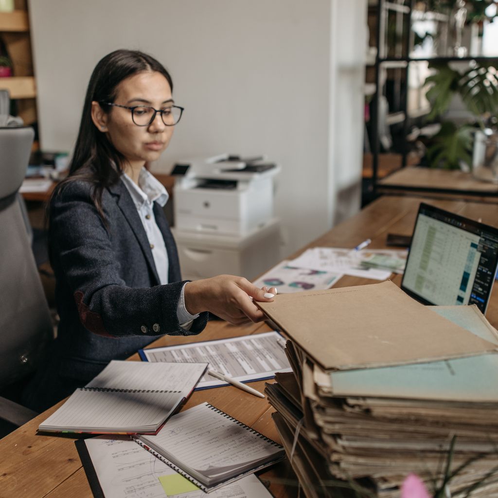 An operations assistant organizing files and records at an office desk