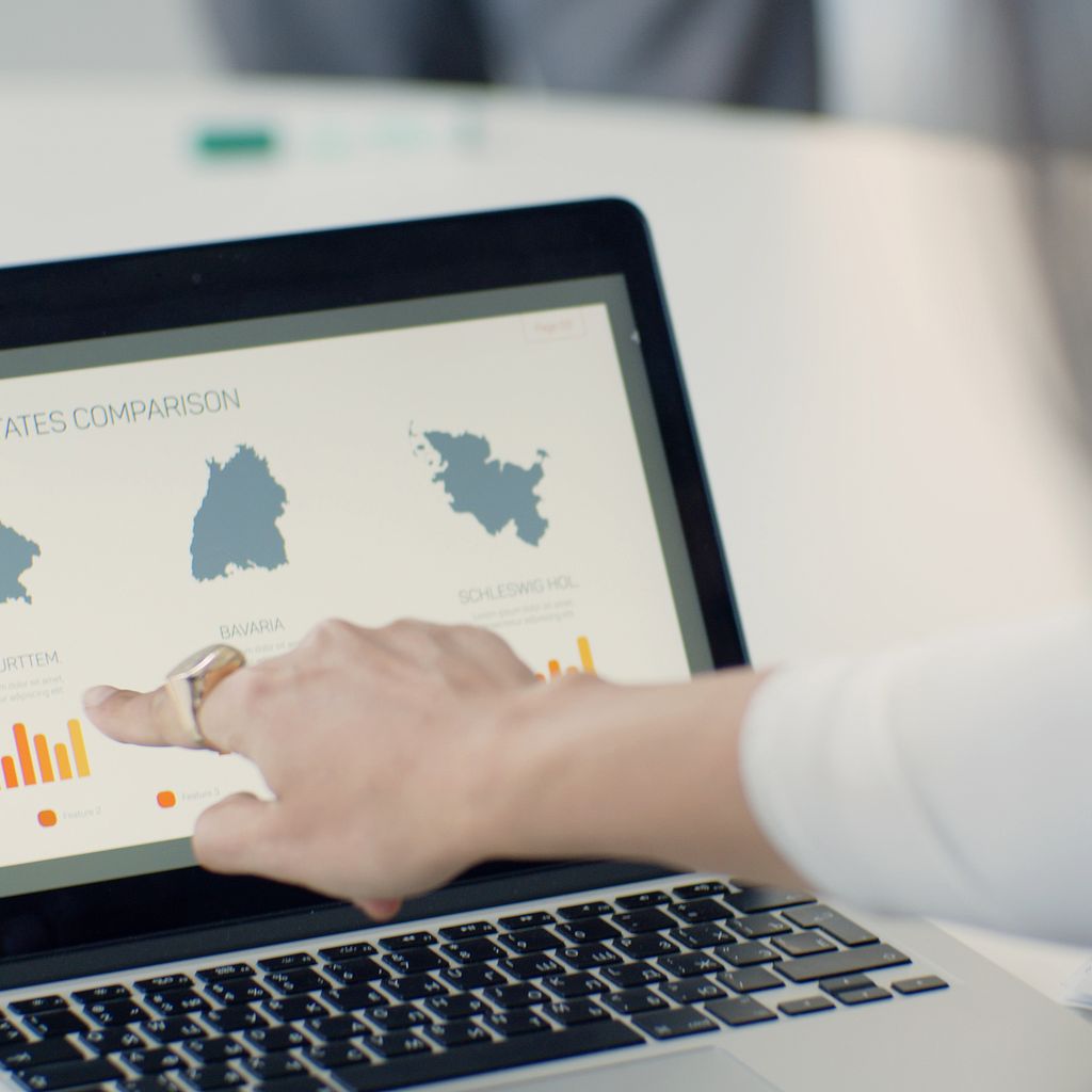 An analyst pointing at a comparison chart on a laptop screen