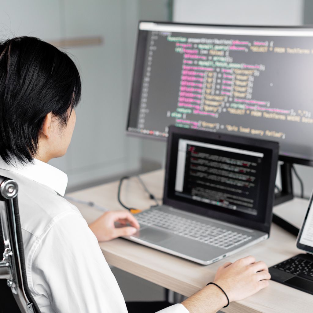 An engineer working on a laptop and an external monitor