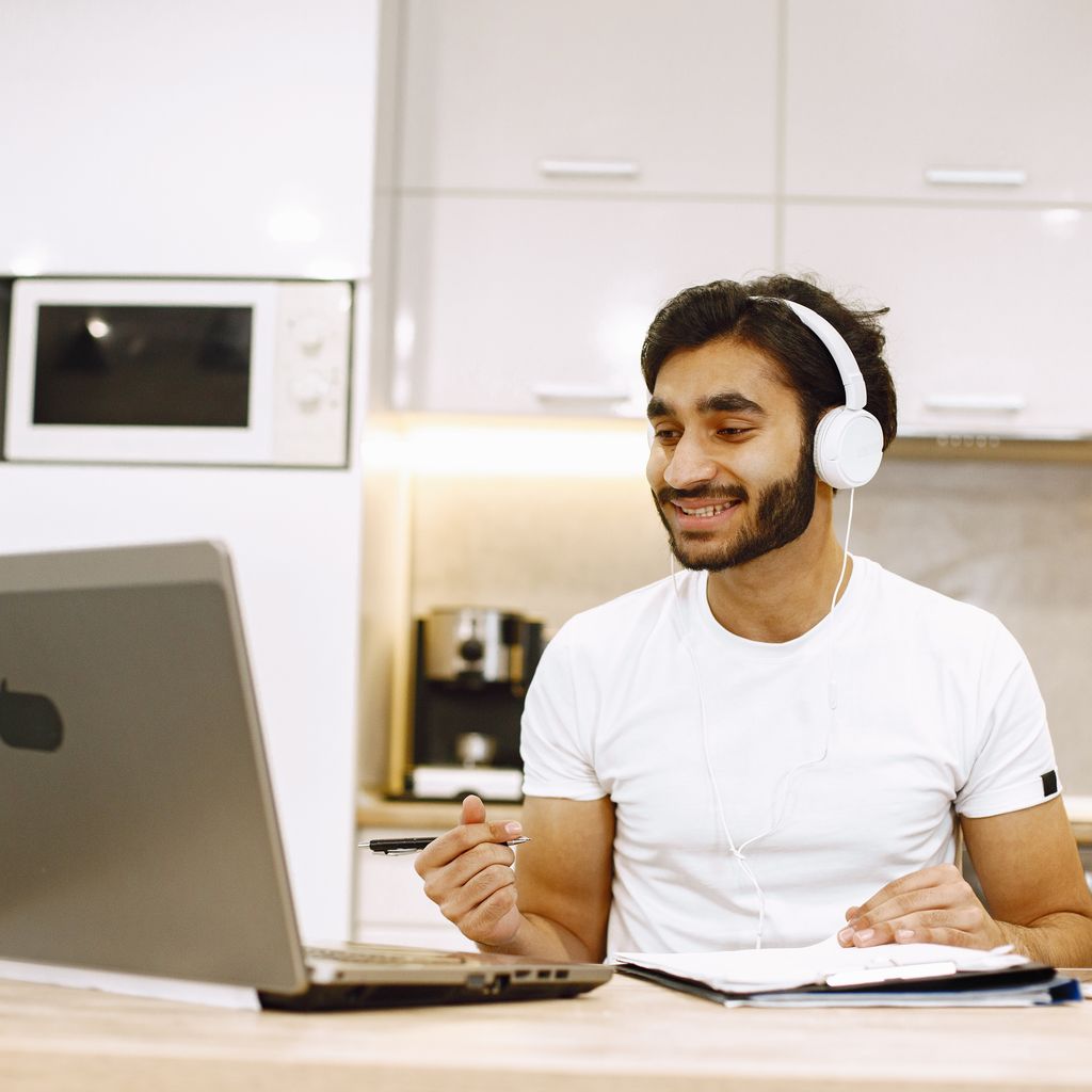 A remote team member working on a laptop with headphones