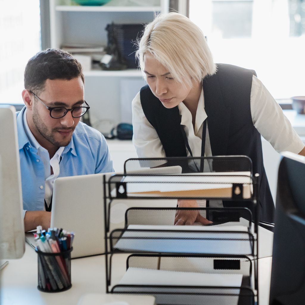 Two colleagues reviewing work together at a laptop