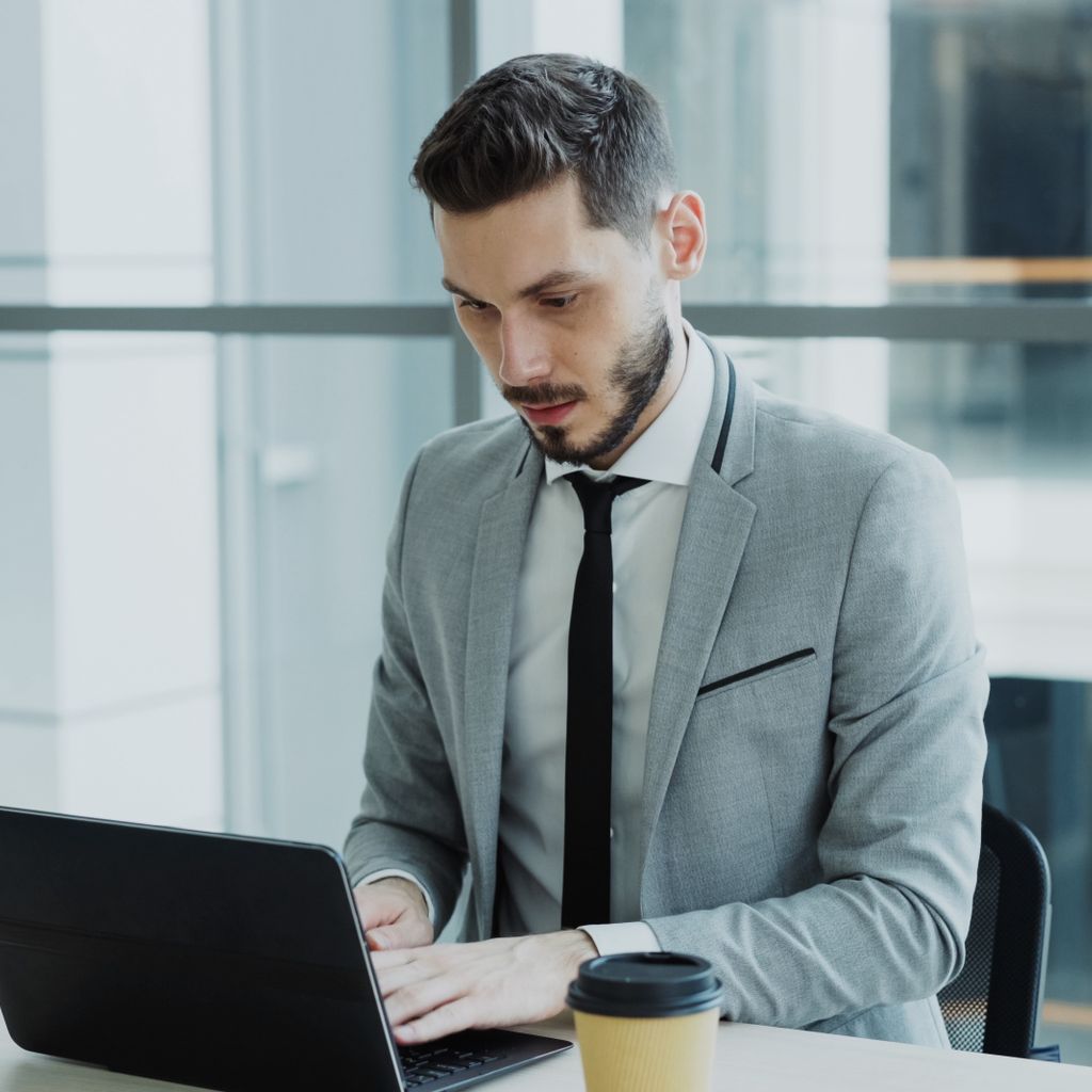 A professional working on a laptop at a desk in a bright office