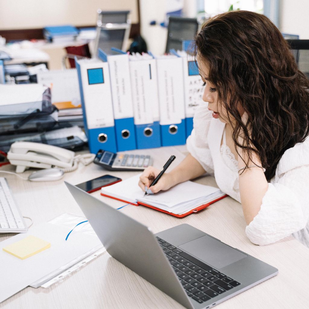 A professional mapping out a process with a notebook and laptop
