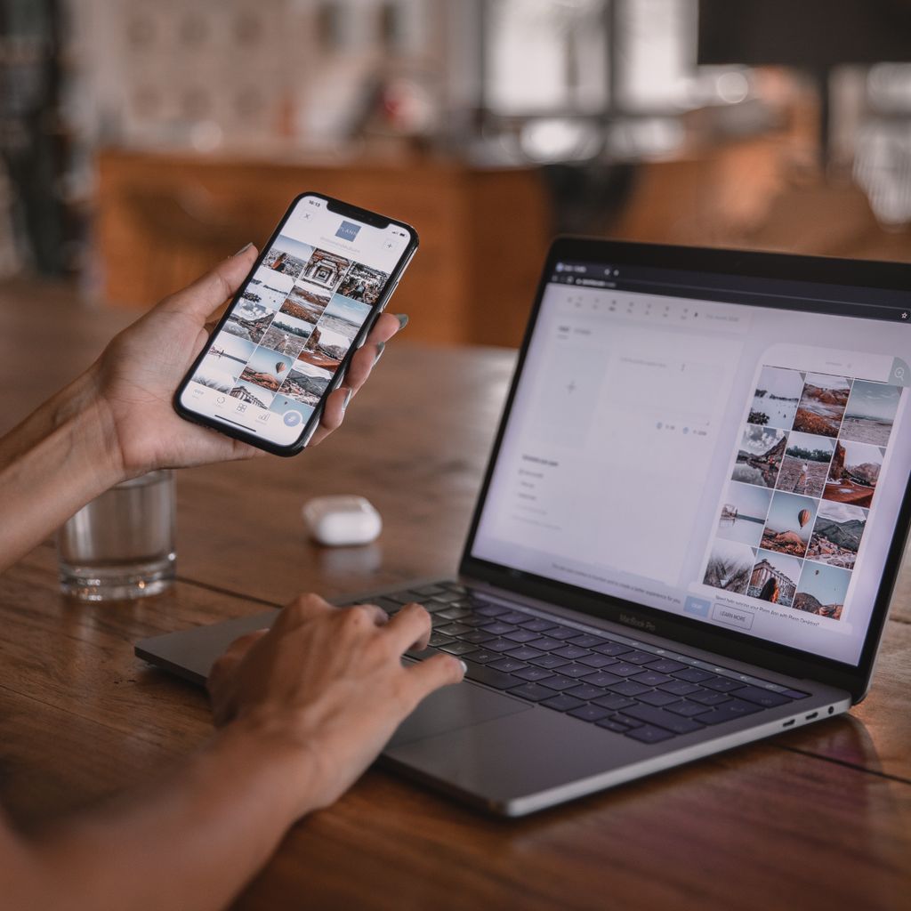 A person checking an app on a phone while working on a laptop