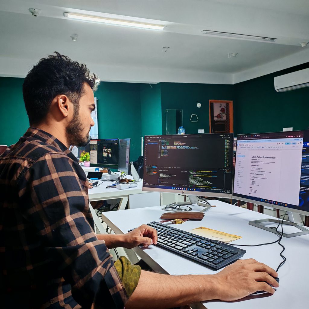 A developer working at a desk with two monitors in an office