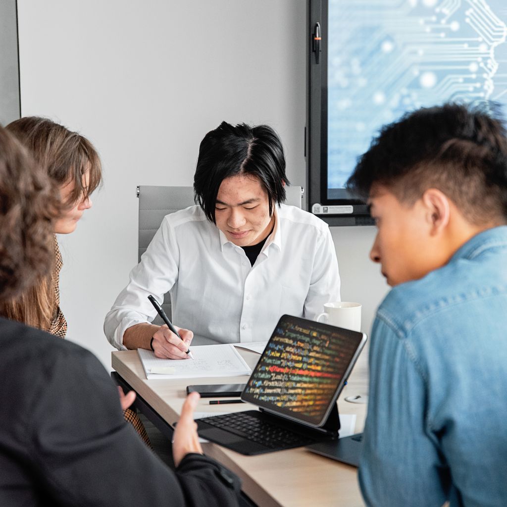 A small software team working together at a table with laptops