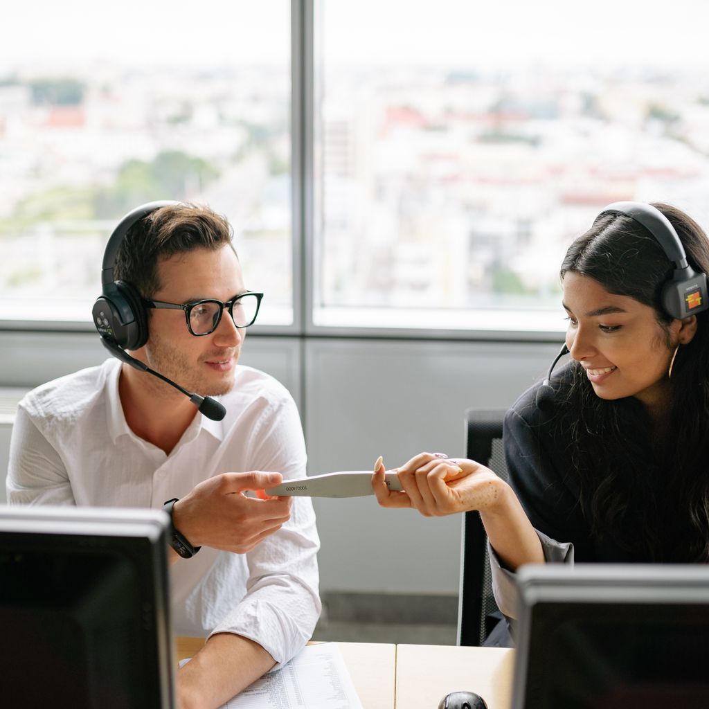 Two sales development reps with headsets working together at their desks