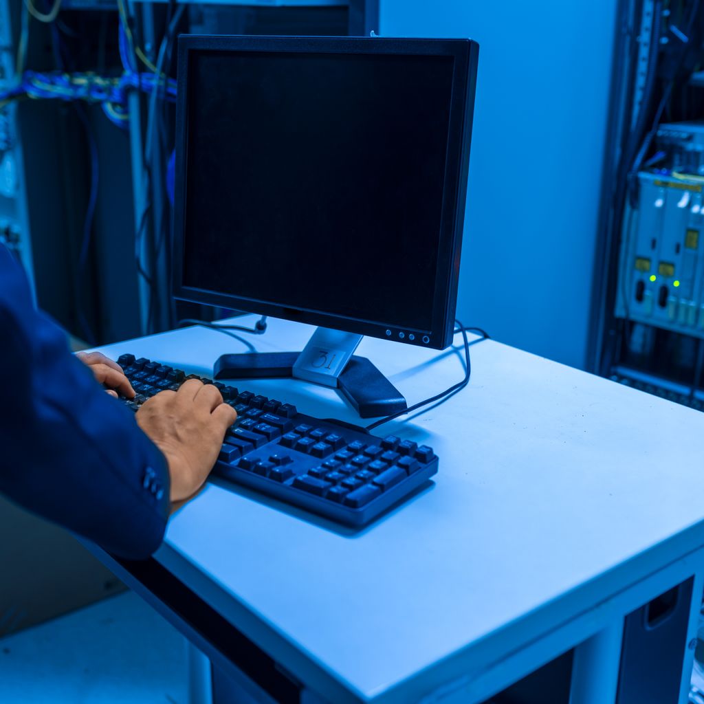 An engineer working at a computer in a server room