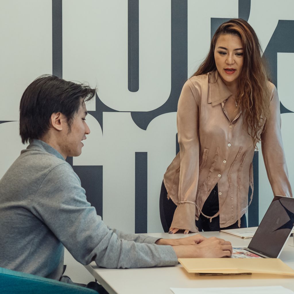 Two colleagues discussing a deal at an office desk