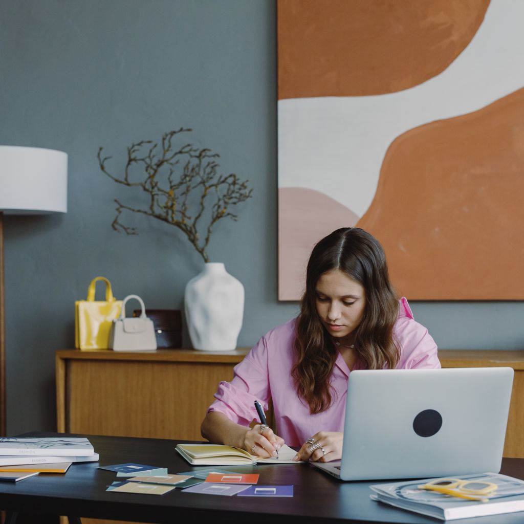 A marketer planning a campaign at her desk with a laptop and notebook